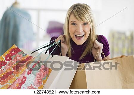 Stock Image - Portrait of woman holding shopping bags. Fotosearch