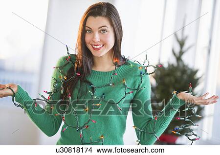 Picture - Portrait of woman tangled in Christmas lights. Fotosearch