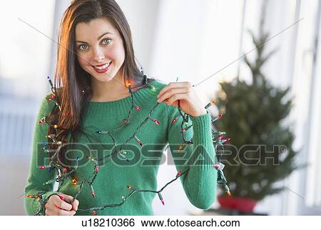 Stock Photograph - Portrait of woman tangled in Christmas lights. Fotosearch