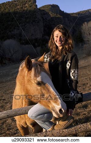 Stock Image - Portrait of young smiling woman with horse. Fotosearch