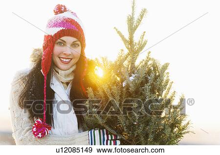 Portrait of young woman carrying Christms tree View Large Photo Image Stock Photo - Portrait of young woman carrying Christms tree. Fotosearch