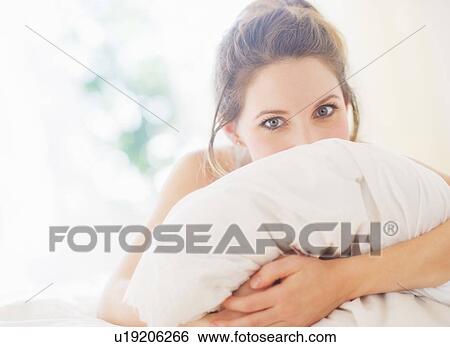 Portrait of young woman embracing pillow in bedroom View Large Photo Image Stock Photograph - Portrait of young woman embracing pillow in bedroom. Fotosearch