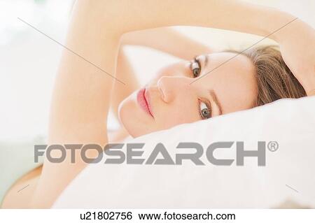 Portrait of young woman lying on bed in bedroom View Large Photo Image Stock Photograph - Portrait of young woman lying on bed in bedroom. Fotosearch