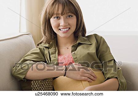 Portrait of young woman sitting on sofa View Large Photo Image Stock Image - Portrait of young woman sitting on sofa. Fotosearch
