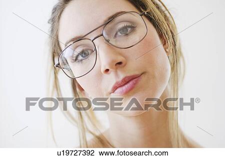 Stock Image - Portrait of young woman wearing glasses, studio shot. Fotosearch