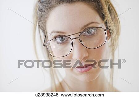 Stock Photograph - Portrait of young woman wearing glasses, studio shot. Fotosearch