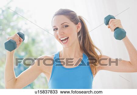 Stock Image - Portrait of young woman with dumbbells. Fotosearch