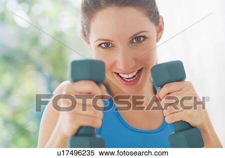 Stock Photography - Portrait of young woman with dumbbells. Fotosearch