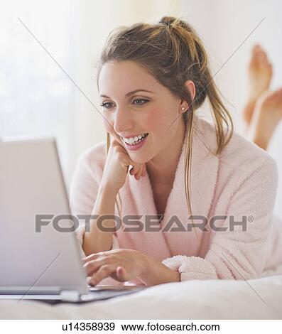 Stock Photo - Portrait of young woman with laptop in bedroom. Fotosearch