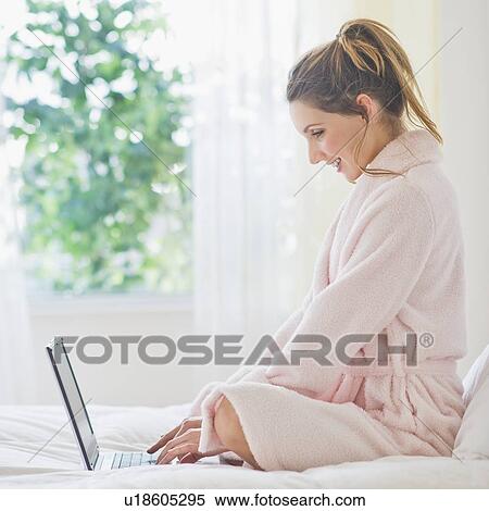 Stock Photography - Portrait of young woman with laptop in bedroom. Fotosearch