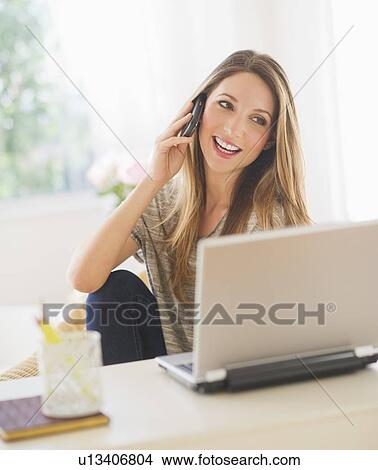 Portrait of young woman working with laptop and mobile phone View Large Photo Image Picture - Portrait of young woman working with laptop and mobile phone. Fotosearch