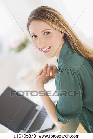 Stock Image - Portrait of young woman working with laptop. Fotosearch