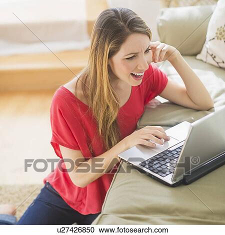 Portrait of young woman working with laptop in living room View Large Photo Image Stock Image - Portrait of young woman working with laptop in living room. Fotosearch