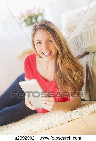 Portrait of young woman working with digital tablet in living room View Large Photo Image Stock Image - Portrait of young woman working with digital tablet in living room. Fotosearch