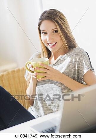 Stock Photo - Portrait of young woman working with laptop and mug. Fotosearch