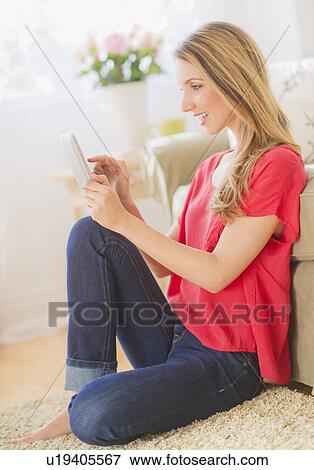 Stock Photo - Portrait of young woman working with digital tablet in living room. Fotosearch