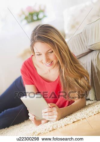 Portrait of young woman working with digital tablet in living room View Large Photo Image Stock Photo - Portrait of young woman working with digital tablet in living room. Fotosearch