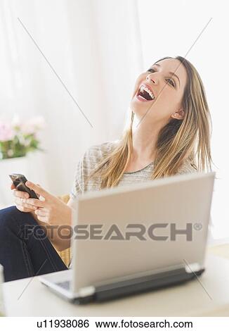 Stock Photograph - Portrait of young woman working with laptop and mobile phone. Fotosearch