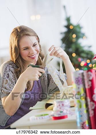 Portrait of young woman wrapping Christmas gifts View Large Photo Image Stock Image - Portrait of young woman wrapping Christmas gifts. Fotosearch