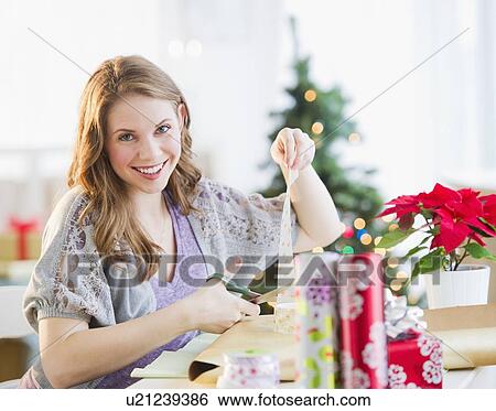 Portrait of young woman wrapping Christmas gifts View Large Photo Image Stock Photograph - Portrait of young woman wrapping Christmas gifts. Fotosearch