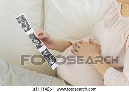 Stock Image - Pregnant woman looking at ultrasound photo. Fotosearch