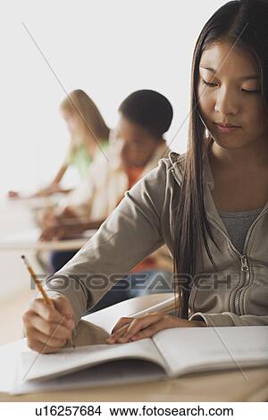 School kid writing in their copybooks View Large Photo Image Picture - School kid writing in their copybooks. Fotosearch