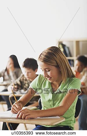 Stock Image - School kid writing in their copybooks. Fotosearch