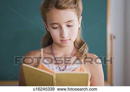 Schoolgirl reading book in front of blackboard View Large Photo Image Stock Photo - Schoolgirl reading book in front of blackboard. Fotosearch
