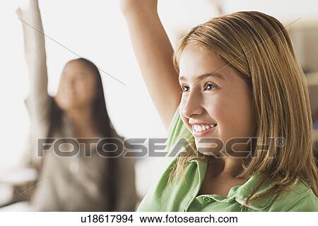 Picture - Schoolgirl rising hand in classroom. Fotosearch
