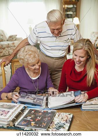 Senior couple and mid adult woman watching family scrapbooks View Large Photo Image Stock Image - Senior couple and mid adult woman watching family scrapbooks. Fotosearch