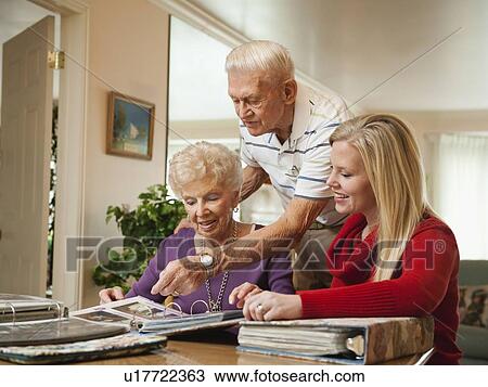 Senior couple and mid adult woman watching family scrapbooks View Large Photo Image Stock Image - Senior couple and mid adult woman watching family scrapbooks. Fotosearch