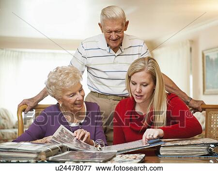 Senior couple and mid adult woman watching family scrapbooks View Large Photo Image Stock Photo - Senior couple and mid adult woman watching family scrapbooks. Fotosearch