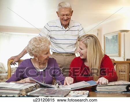 Senior couple and mid adult woman watching family scrapbooks View Large Photo Image Stock Photography - Senior couple and mid adult woman watching family scrapbooks. Fotosearch