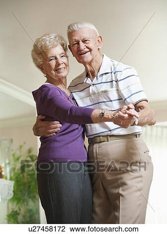 Stock Image - Senior couple dancing at home. Fotosearch