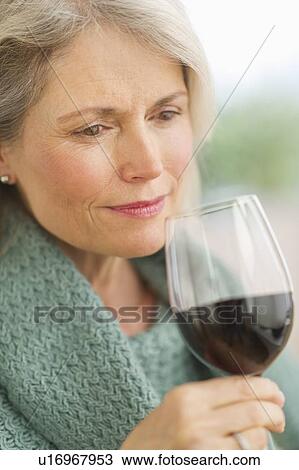 Stock Image - Senior female connoisseur tasting red wine. Fotosearch