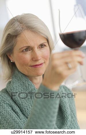 Stock Photo - Senior female connoisseur tasting red wine. Fotosearch