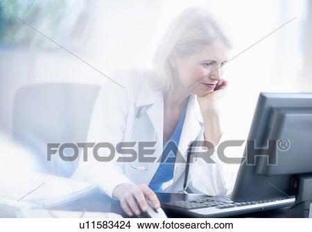 Picture - Senior female doctor working in her office. Fotosearch