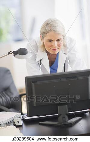 Picture - Senior female doctor working in her office. Fotosearch