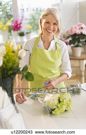 Stock Image - Senior female florist arranging bouquet. Fotosearch