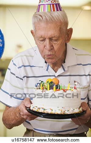 Senior man blowing candles on birthday cake View Large Photo Image Stock Photo - Senior man blowing candles on birthday cake. Fotosearch