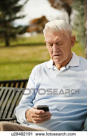 Senior man using phone in park View Large Photo Image Stock Image - Senior man using phone in park. Fotosearch
