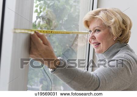 Stock Image - Senior woman measuring window. Fotosearch