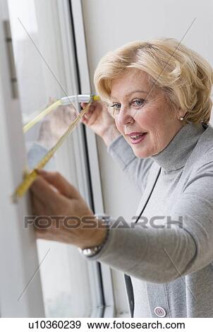 Senior woman measuring window View Large Photo Image Stock Photo - Senior woman measuring window. Fotosearch
