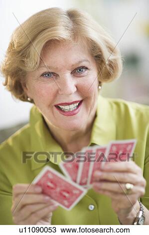Stock Image - Senior woman playing cards. Fotosearch