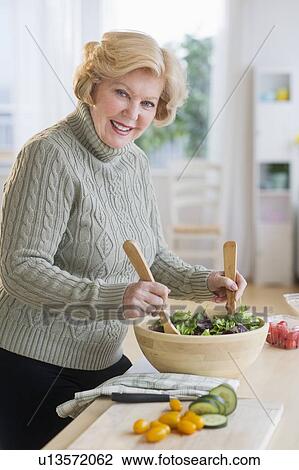 Stock Image - Senior woman preparing salad . Fotosearch