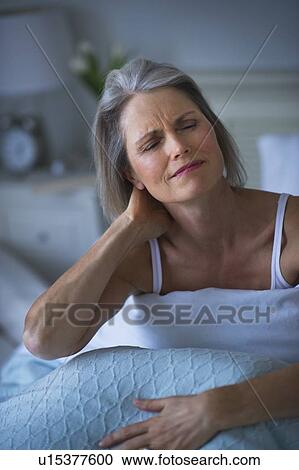 Senior woman sitting in bed and suffering from necklace View Large Photo Image Stock Image - Senior woman sitting in bed and suffering from necklace. Fotosearch