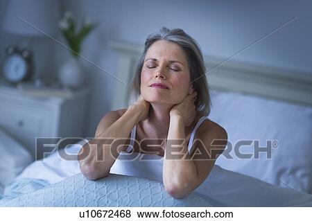 Stock Photo - Senior woman sitting in bed and suffering from necklace. Fotosearch