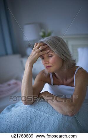 Senior woman sitting in bed and suffering from headache View Large Photo Image Stock Photo - Senior woman sitting in bed and suffering from headache. Fotosearch