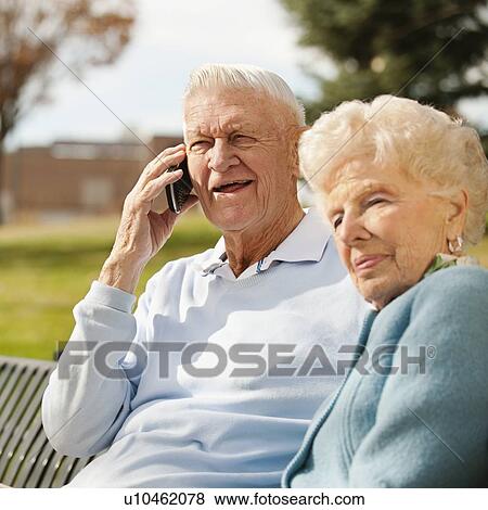 Senior woman with man using phone in park View Large Photo Image Stock Photo - Senior woman with man using phone in park. Fotosearch