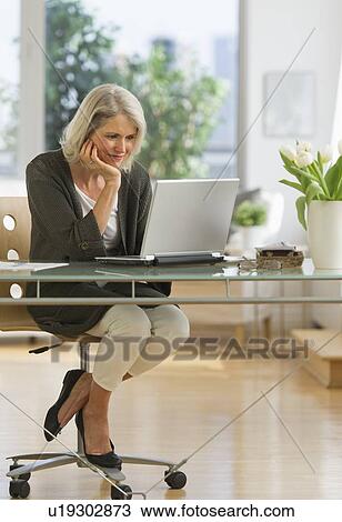Stock Image - Senior woman working from home. Fotosearch
